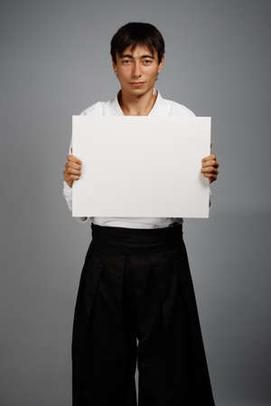 Smiling man in kimono on grey background with business cardの写真素材