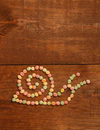 Beautiful snail design made of colorful candies on wooden background in style of children's art.の写真素材