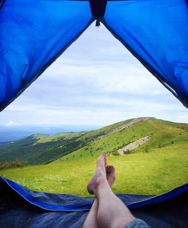 Image human legs lying in tourist tent with view of the mountainsの写真素材