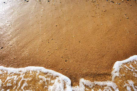 Sea wave on orange pebble sand beach. Abstract background with copy space.