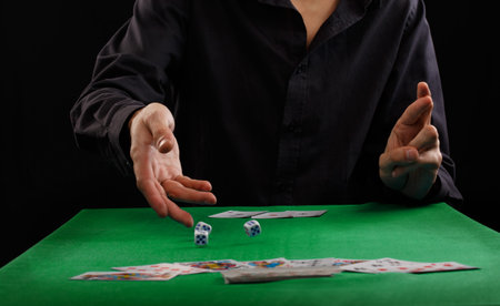 Man throwing dice on a gambling table with playing cards