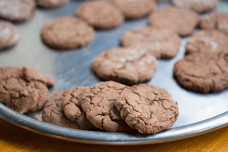 Brown tasty chocolate cookies with crackles lay at metal tray. Shallow dof. Focus on foreground.の写真素材