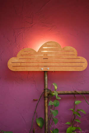 Original interior with wooden cloud and sun lamp decoration, pipes with artificial plants on it at the background of purple colored wall.の写真素材