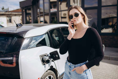 Woman charging electro car at the electric gas stationの写真素材