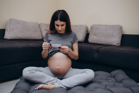 Pregnant woman with ultrasound photo sitting on bed