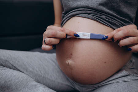 The concept of a pregnant woman holding a pregnancy test and remembering how she first learned about pregnancyの写真素材