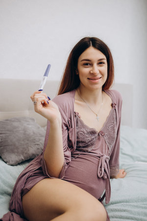 Smiling woman looking at pregnant test. Isolated portrait of young expectant mother.