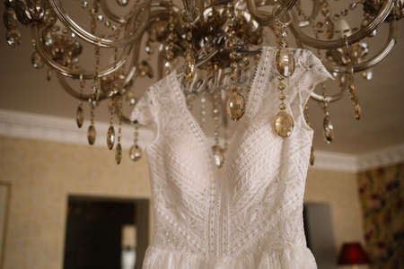 beautiful white dress for the bride hanging on chandelierの写真素材