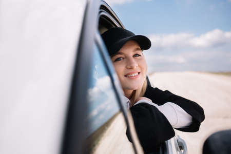 Beautiful girl driving a car, smiling in the side mirror of the carの写真素材