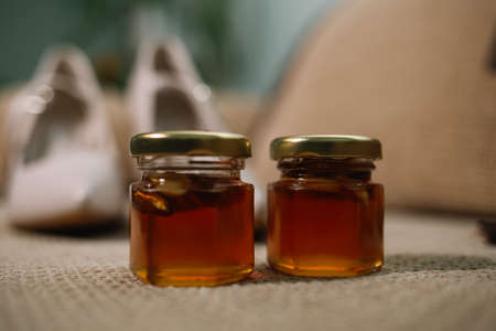 two jars of honey and wooden drizzler on table on yellow backgroundの写真素材