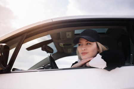 Young beautiful smiling woman driving a car. Her cute daughter sitting on rear and enjoying.