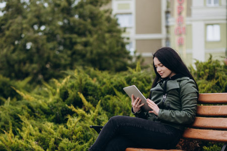 Happy hipster young woman working on laptop in the park