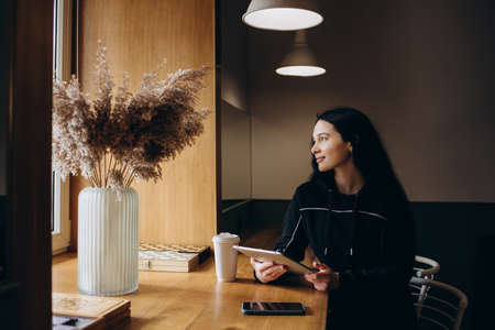 Focused business woman sit on cafe working on laptop, concentrated serious female working with computer and notebook in coffee shop, freelancer, studying online, browse internet, checking billsの写真素材
