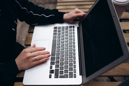 Close up of woman using blank laptop order products for shopping online within the cafe.