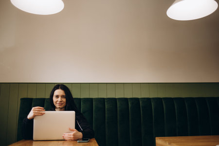 Attractive female freelancer chatting with her friends while sitting front open computer in vintage...