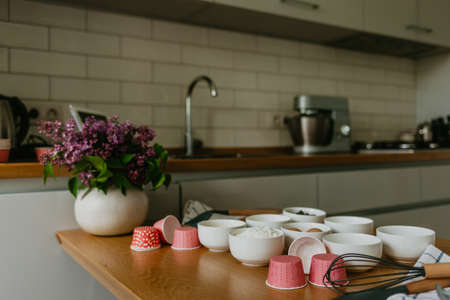 Variety of cupcake liners in different colors with a muffin pan and wire whiskの写真素材