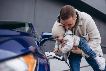 A father with his young daughter is charging an electric carの写真素材