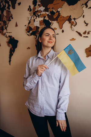 Young girl with school stuff holds in hand Ukraine flag close upの写真素材