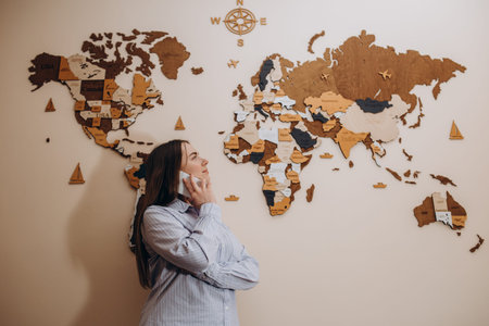 Photo of female travel agent. Young woman talking on phone, smiling and looking at camera. Travel...