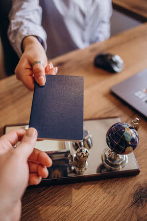 Agent giving passport and ticket to customer in the office of travel companyの写真素材