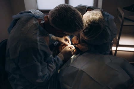 Surgeon and his assistant performing cosmetic surgery on nose in hospital operating room. Nose reshaping, augmentation. Rhinoplasty.の写真素材