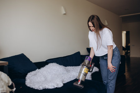 Young woman with rechargeable vacuum cleaner cleaning at home.の写真素材