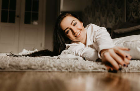 Beautiful brunette girl in a man's white shirt at home,の写真素材