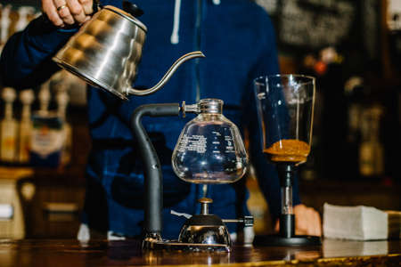 brewing coffee siphon. step by step cooking instructions. pouring siphon into the flask from the kettle of hot waterの写真素材