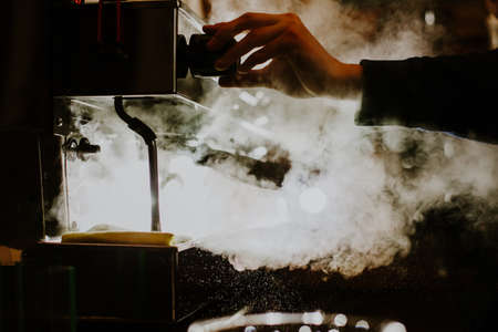 Close-up image of female barista using coffee-making machine to steam milk in cafeの写真素材