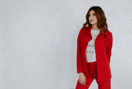 portrait of young business woman in red suit with arms up. isolated on white background. business...