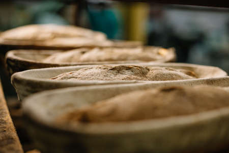 Baking bread. Dough in proofing basket on wooden table with flour, cumin and wheat ears. top view.の写真素材
