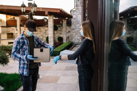 Woman parcel receiving from delivery man at the door. medical mask, quarantine