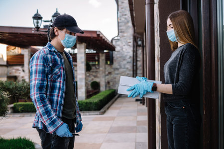 Contactless delivery service during quarantine. Man delivers food and shopping bags during...