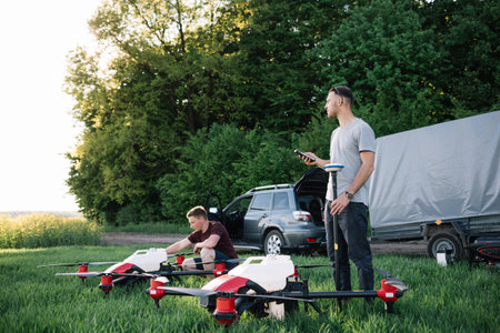 Attractive two farmers navigating drone above farmland. High technology innovations for increasing...
