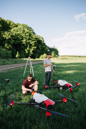 A drone pilot configuring his drone in a field with and irrigation system before flying
