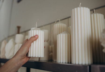 DIY wax candle making process. Woman making decorative wax candle and decorates with dried flowers, close-up of handsの写真素材