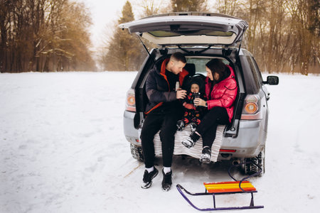 Happy family near car outdoors during snowfall. winter holidays.の写真素材