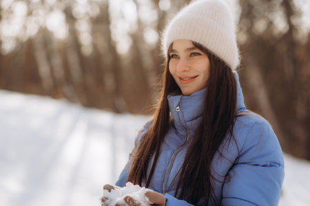 Winter girl blowing snow. Beauty Joyful Teenage Model Girl having fun in winter park. Beautiful young woman laughing outdoors. enjoying nature.の写真素材