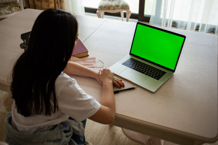 Over The Shoulder View Of Woman Lying On Sofa Using Green Screen Laptopの写真素材