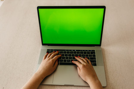 Asian girl using laptop with green screen.
