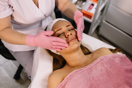 Doctor massaging patient's face. Model and doctor. Cosmetic clinic. medical equipment. Healthcare, clinic, cosmetologyの写真素材