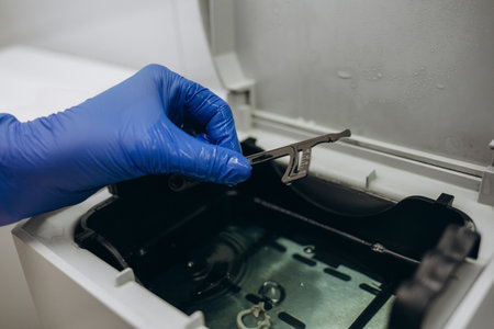 Close-up hands with gloves in the places medical autoclave for sterilizing surgical and dental instruments. Dentist assistant's hands get out sterilizing medical instruments from autoclave.の写真素材