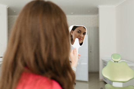 Young woman checking their teeth at mirror after dental treatment - People bodycare and stomatology concept for healthy lifestyle - Focus on girl face -の写真素材