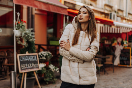 Feeling warm and protected. European winter. girl warm coat stairs background. faux fur coat fashion. stylish business lady leather bag. glamor girl look luxuriously. sexy blonde woman. autumn season.の写真素材