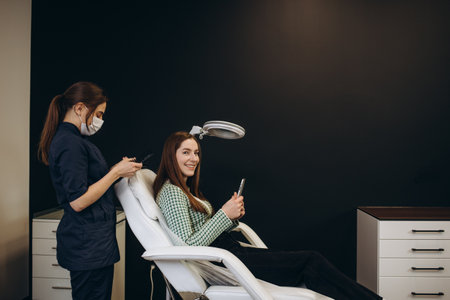 Doctor examines head skin of a young girl with special dermatology equipment system, hairloss and trichology concept Woman Analyzing Hair With Analysis System.の写真素材