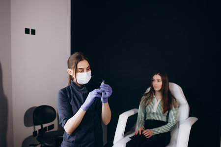 Doctor trichologist examines woman patient's hairs using trichoscope in clinic. Procedure of trichoscopy hair. Runs a trichoscope over scalp and looks result on monitor screen. Computer trichoscopy.の写真素材