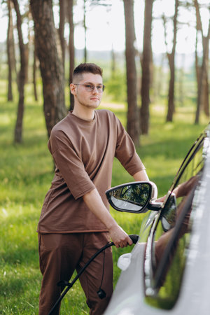 Man charging electric car by the houseの写真素材