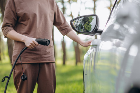 Color image of a man's hand preparing to charge an electric car.の写真素材