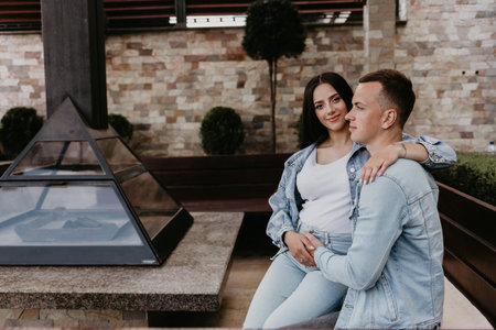 Young man hugging his beautiful smiling pregnant wife sitting near the burning fireplace. Pregnancy conceptの写真素材
