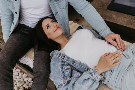 Young beautiful pregnant woman sitting on windowsill at homeの写真素材